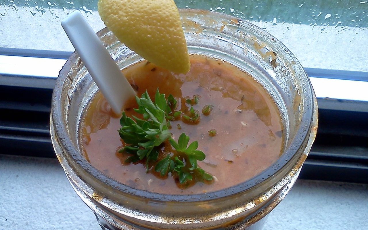 Red-orange lentil, rice, and bulgur soup in a bowl with lemon