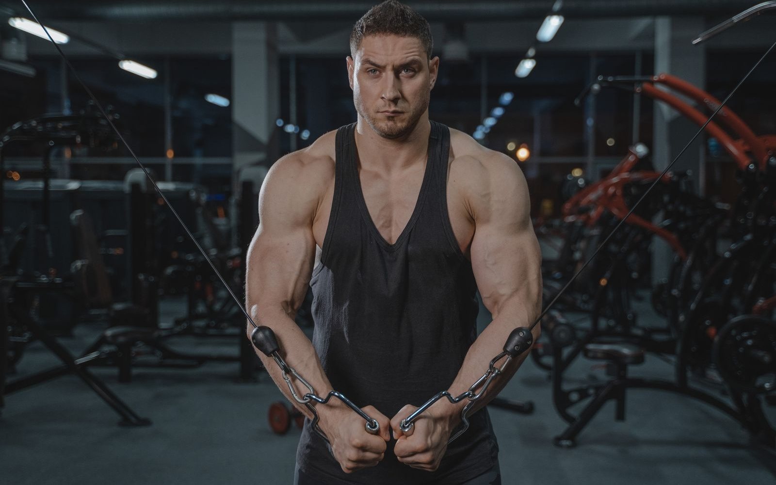 Man performs a standing cable crossover in a gym.