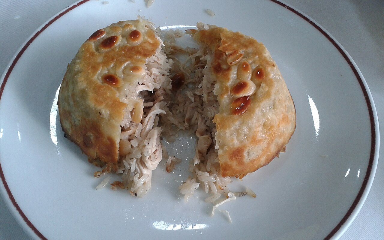 Domed golden perde pilavı studded with almonds and sliced to reveal chicken rice