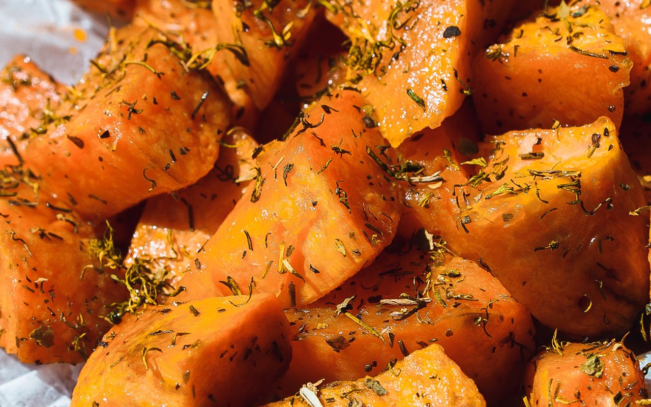 Roasted sweet potato slices with garlic and rosemary on a sheet pan