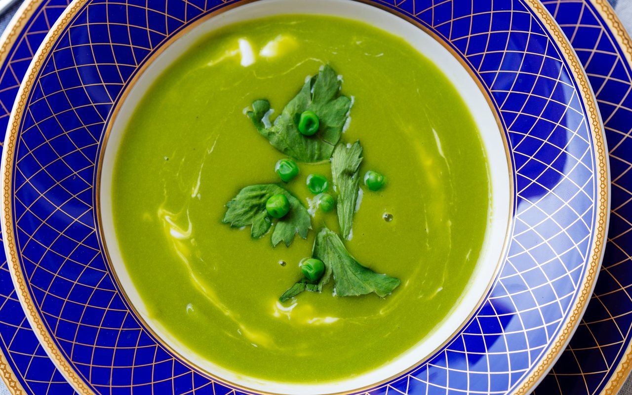 Smooth green pea soup with dill in a white bowl