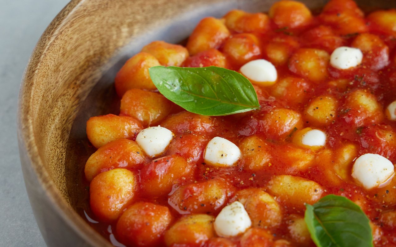Potato gnocchi in red tomato sauce with mozzarella pearls and fresh basil