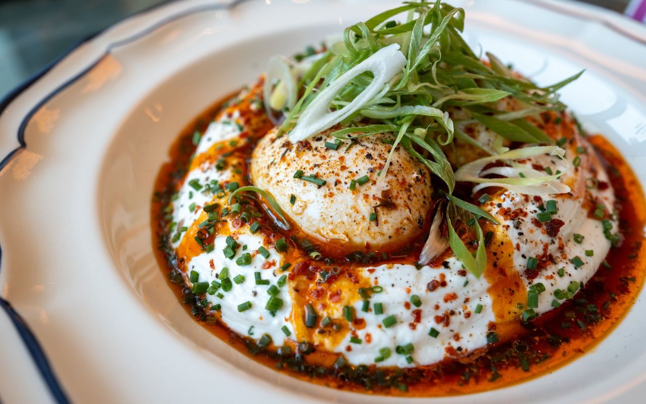 Poached eggs on garlic yogurt with red pepper butter in a shallow serving bowl