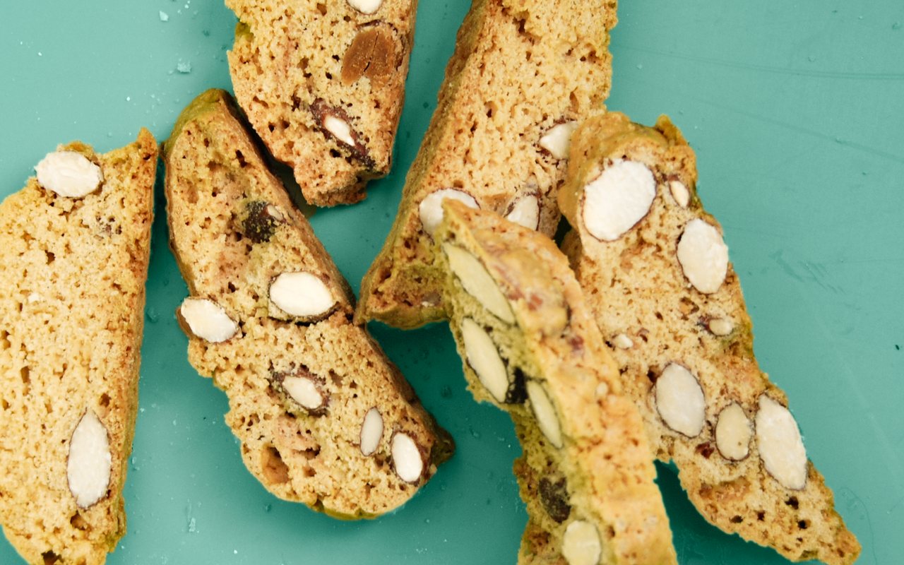 Twice-baked biscotti slices with dried fig and almond pieces on a baking tray