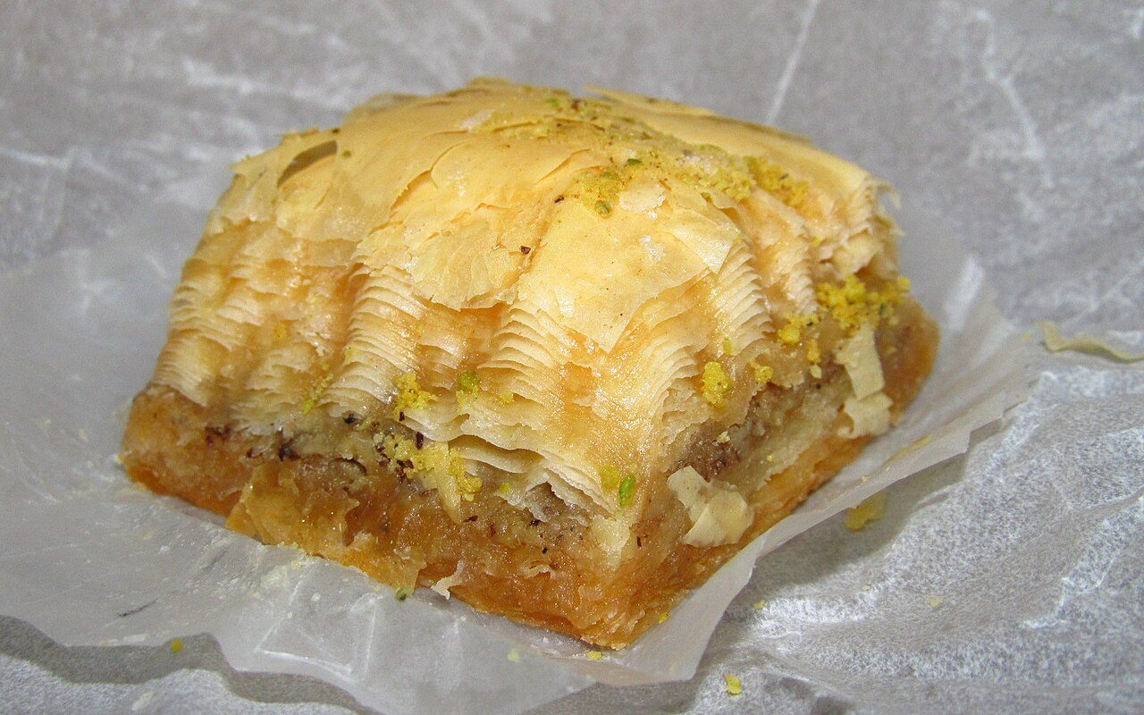 Tray of diamond and triangular walnut baklava with glossy syrup-soaked layers