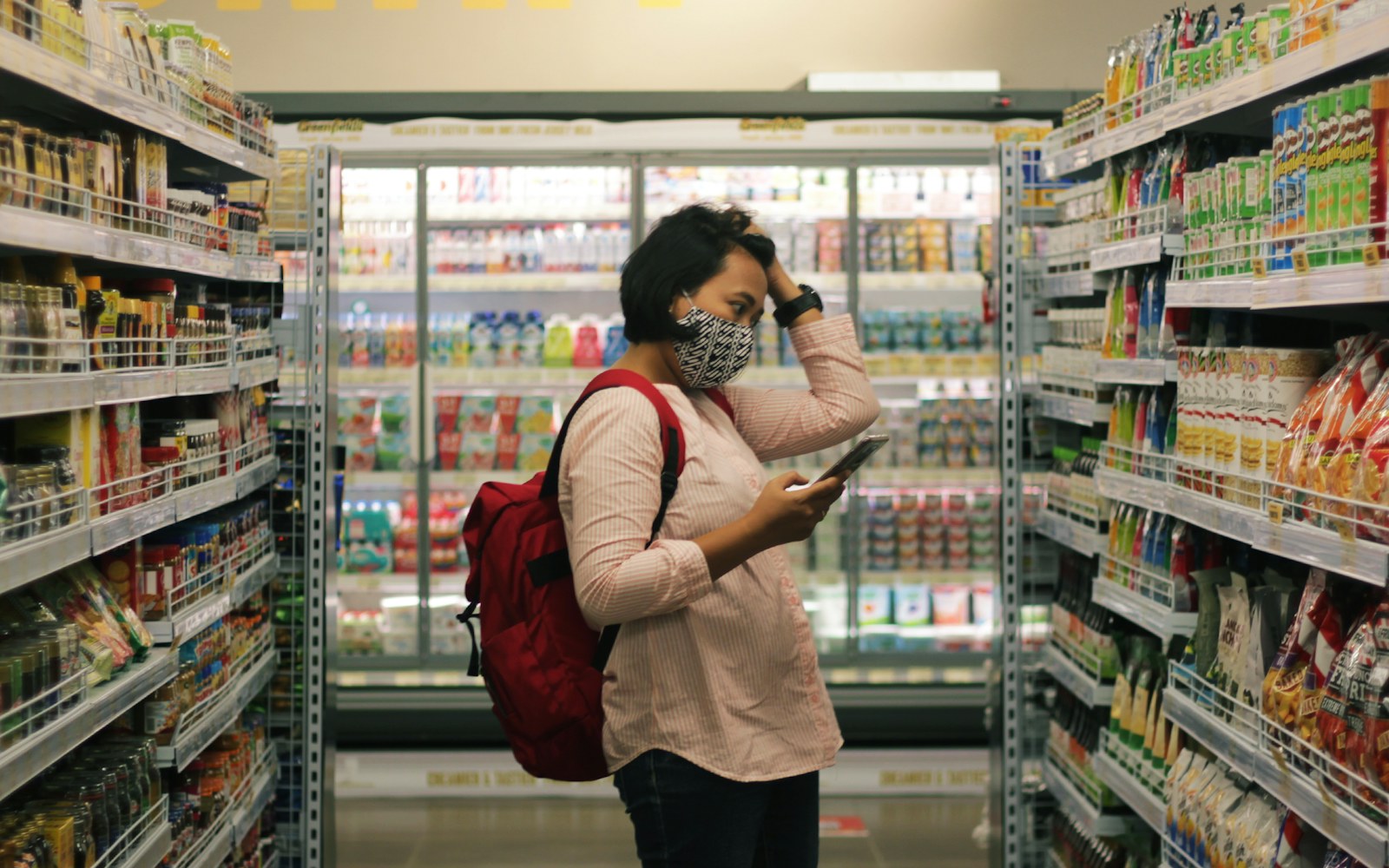 Shopper checks a smartphone between grocery-store shelves