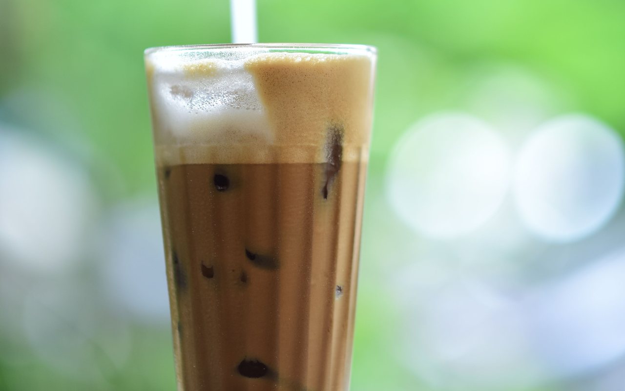Tall glass of iced coffee with a thick foam cap