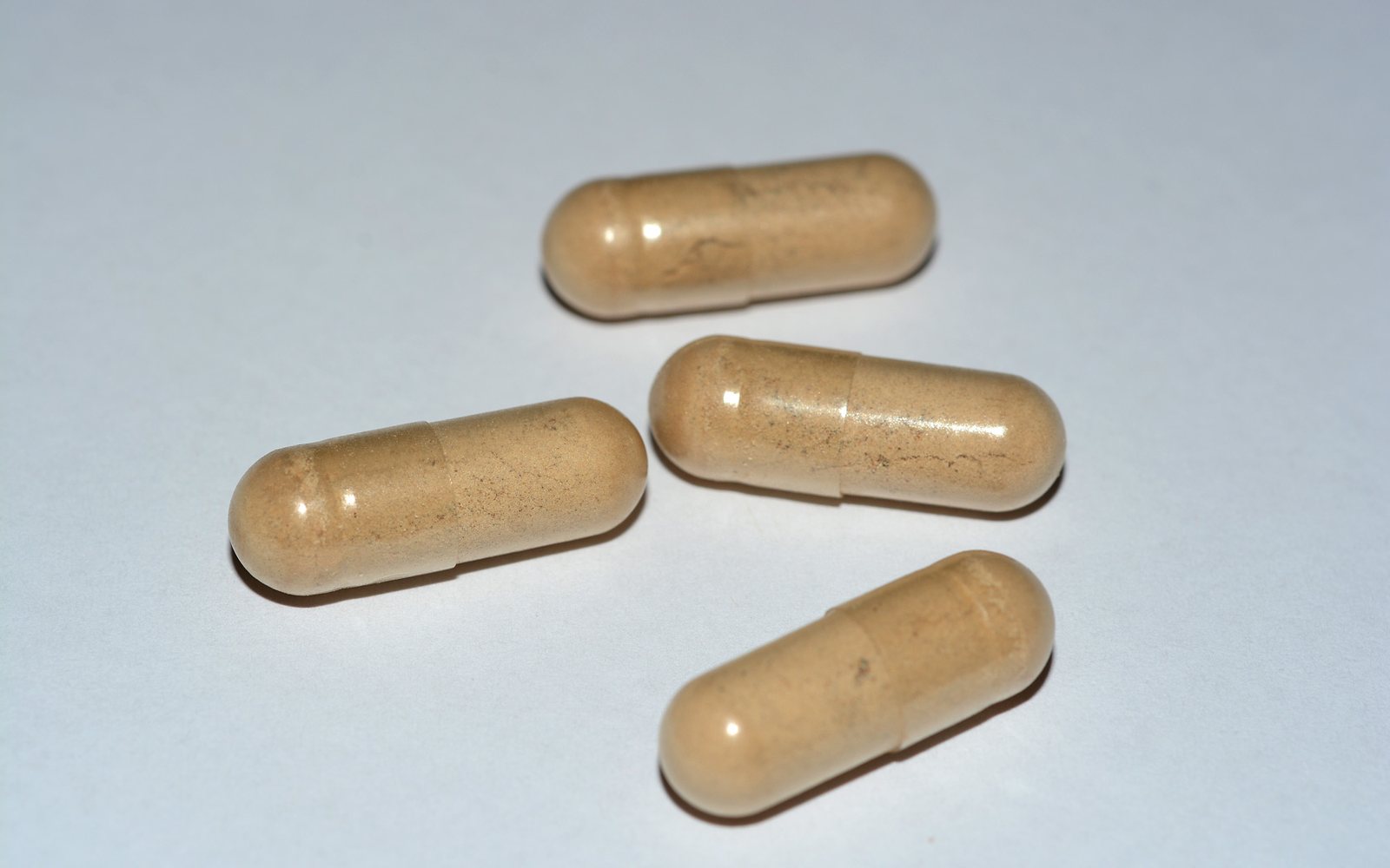Four tan capsules arranged on a plain white surface.