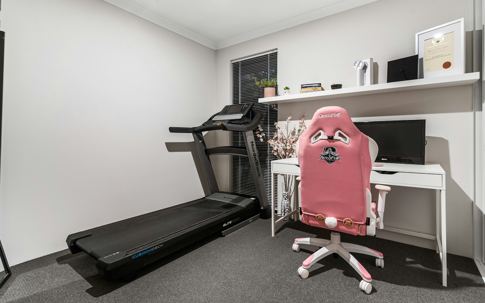 Treadmill positioned beside a desk in a home office