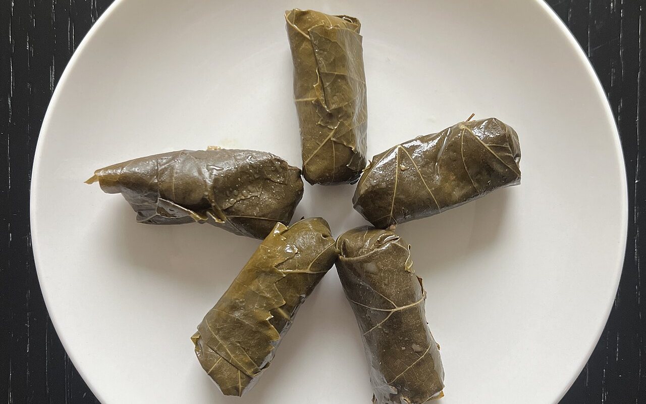 Rows of olive-oil stuffed grape leaves garnished with lemon slices