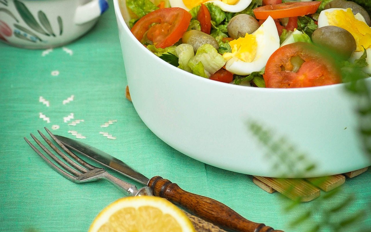Hard-boiled egg wedges with lettuce and sliced tomatoes in a white salad bowl