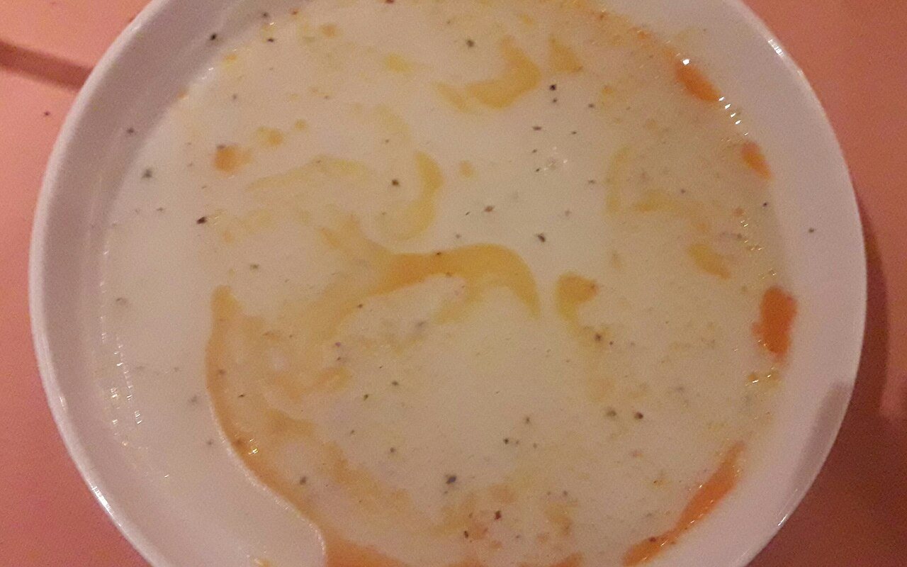 Creamy yogurt soup topped with melted butter and dried mint in a shallow bowl