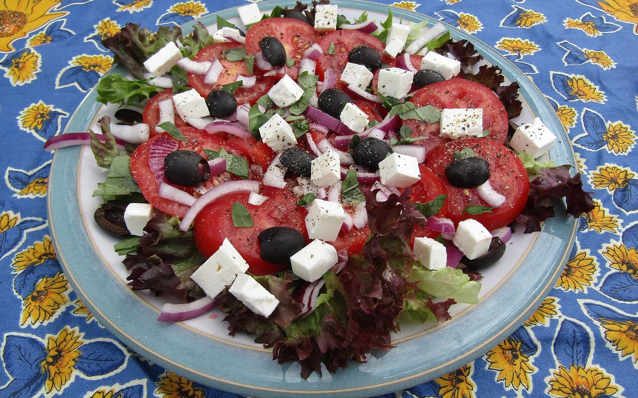 Greek salad with large tomato, cucumber, red pepper, onion, olive, and feta pieces