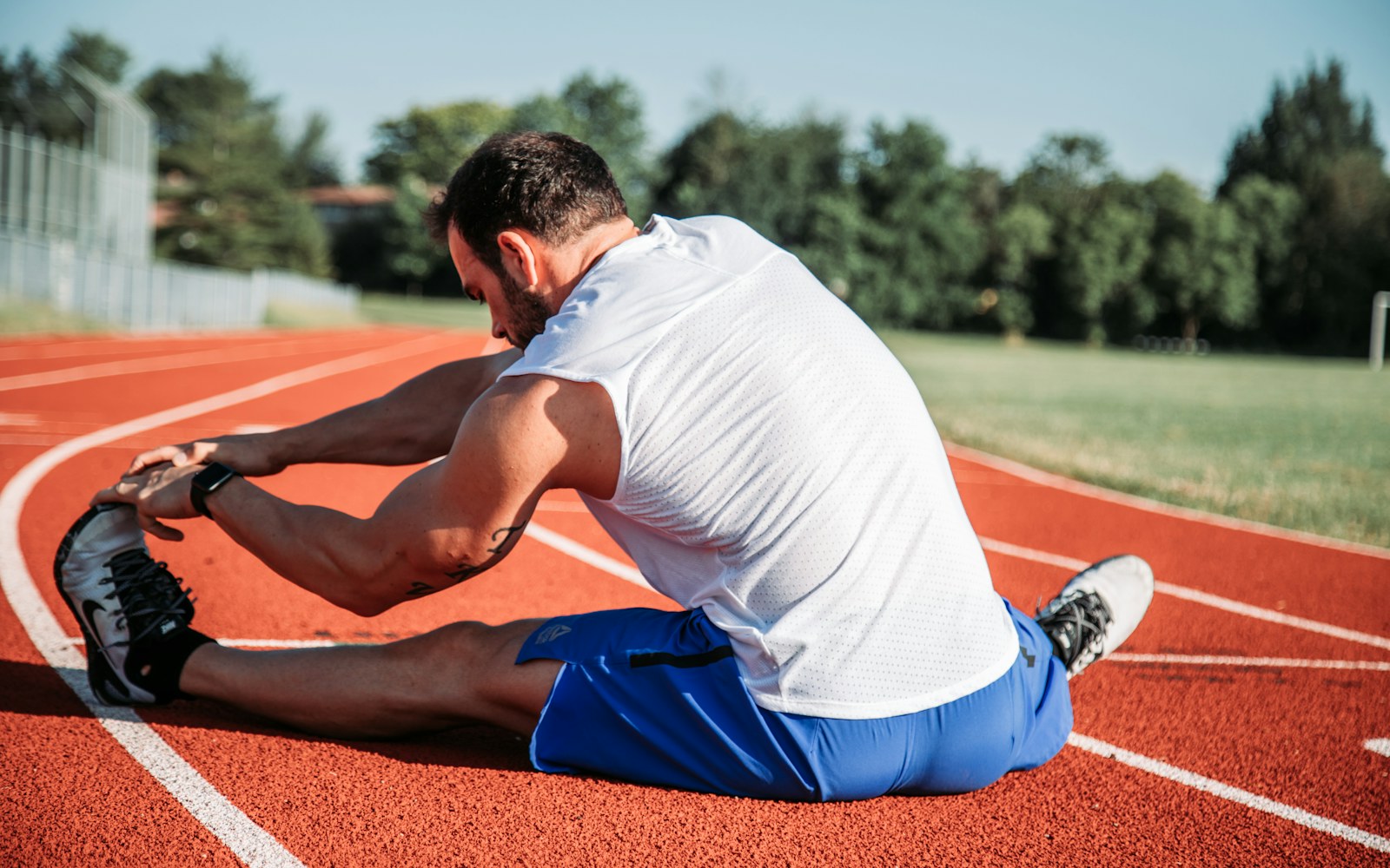 Runner stretches one leg on an outdoor track