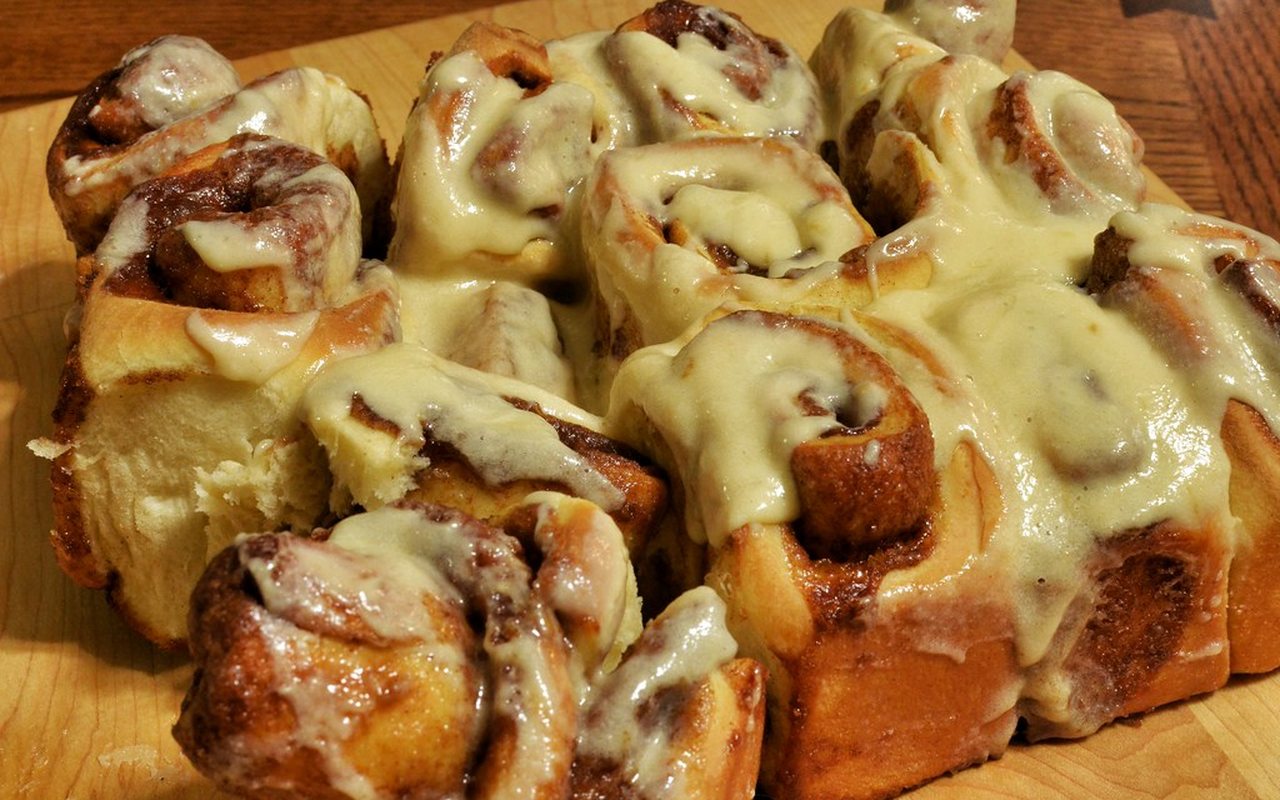 Soft spiral cinnamon rolls covered with pale labneh frosting in a baking dish