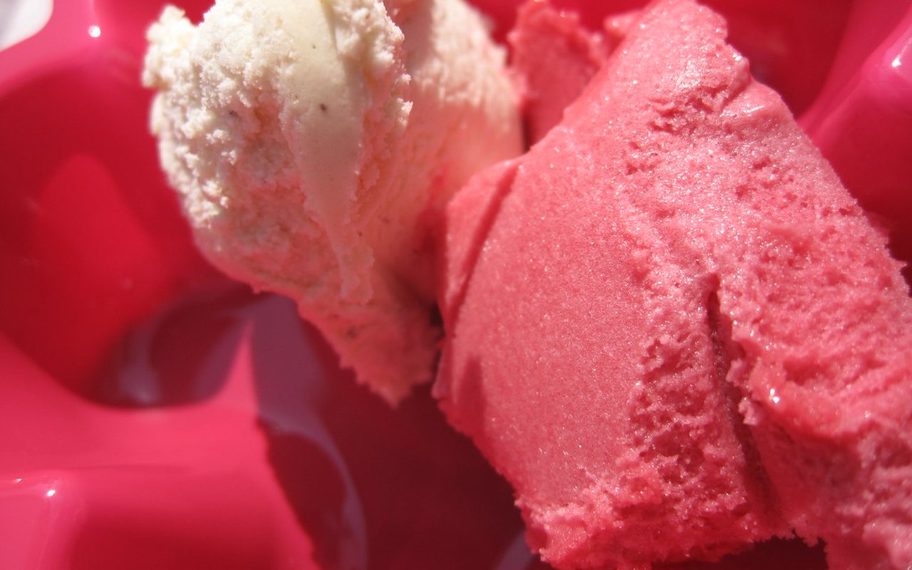 Scoops of pale pink strawberry ice cream in a serving bowl with fresh strawberries