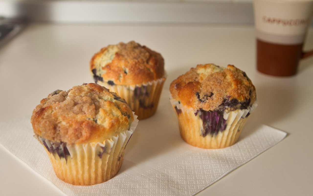 Blueberry muffins in paper liners with berries visible on top