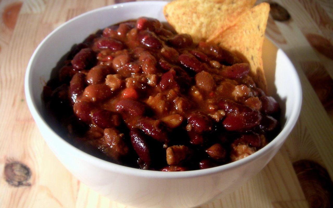 A bowl of beef chili with red beans, corn, tomatoes, and chile peppers