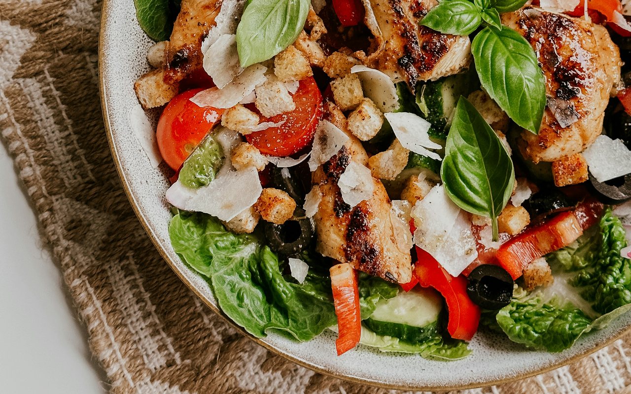 Mediterranean chicken salad with tomatoes, black olives, cucumbers, peppers, greens, and cheese.