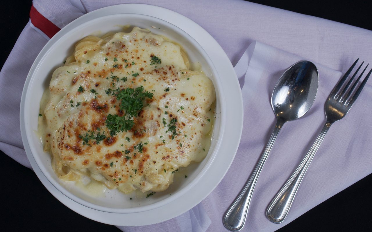 A square slice of baked pasta topped with browned melted cheese