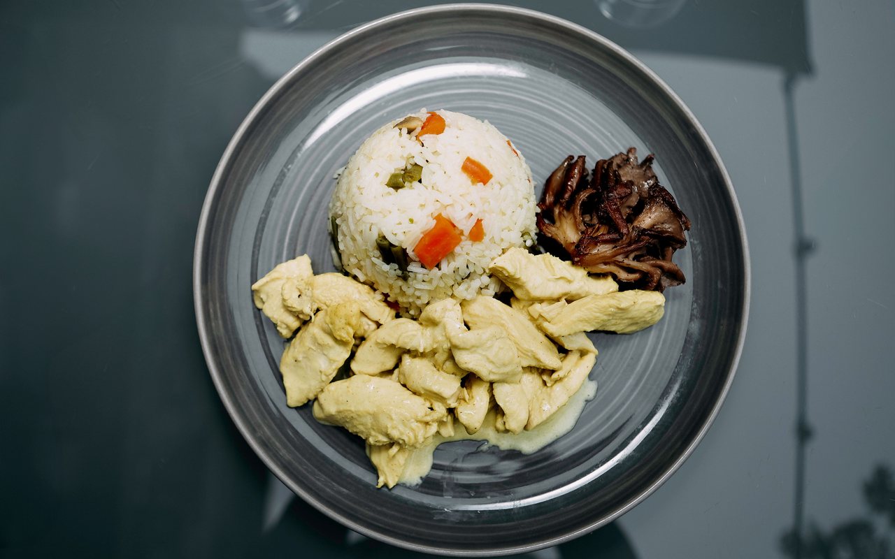 Creamy chicken breast pieces served with vegetable rice and a roasted mushroom cluster
