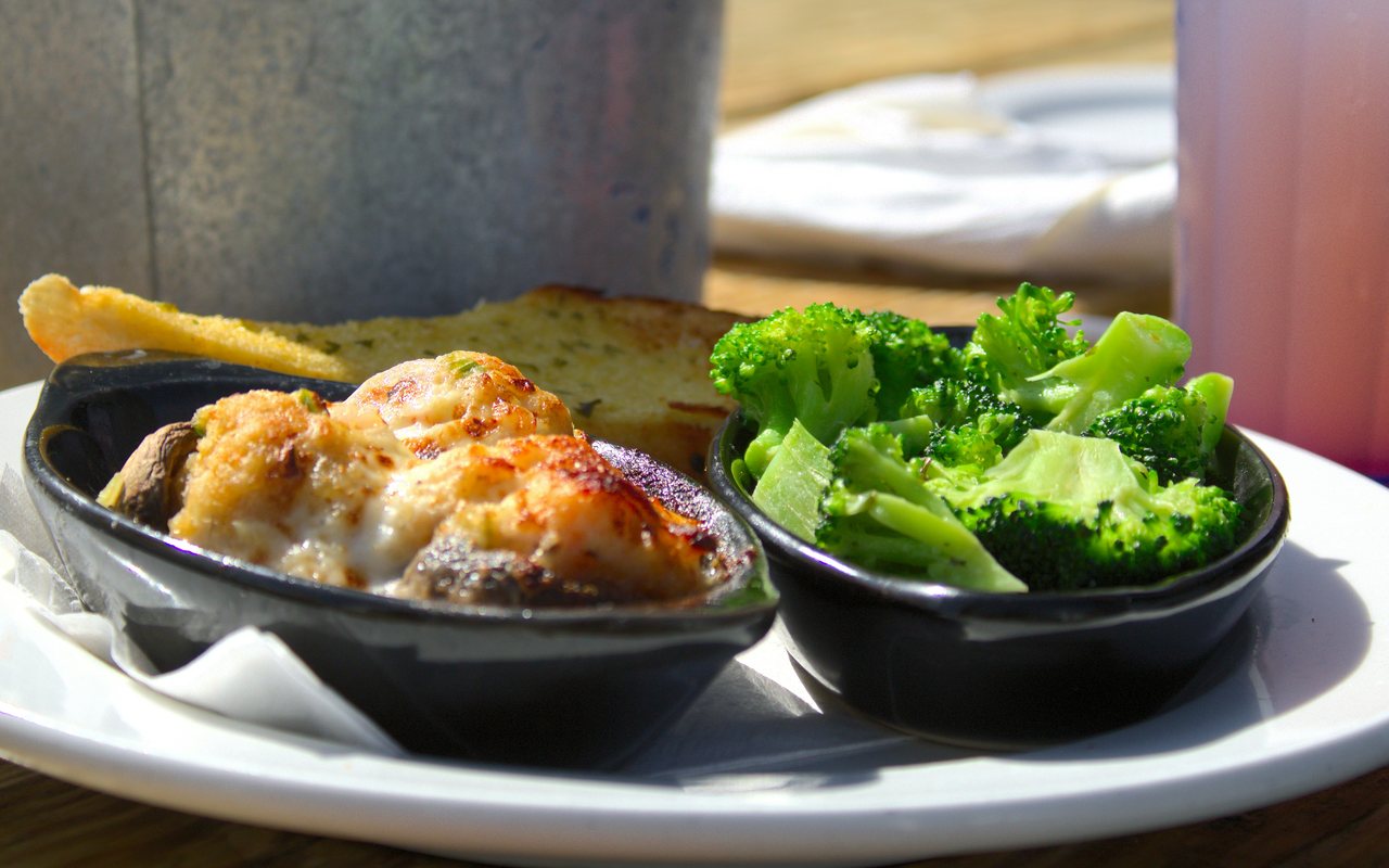 Stuffed mushroom caps served with broccoli and lemon wedges.