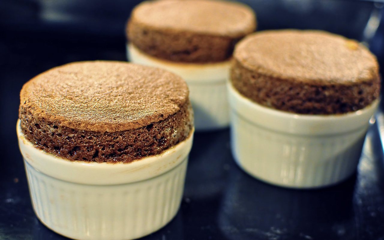 Three risen chocolate soufflés dusted with powdered sugar